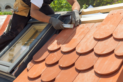 Natural roof tile instaalation. Roofer builder worker use ruller to measure the distance between the tiles. Roof with mansard windows.